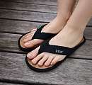Feet wearing black REuse me flip-flops with cork sole – sustainable reusable bath slippers at Sunstar Hotel.