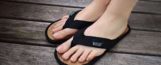 Feet wearing black REuse me flip-flops with cork sole – sustainable reusable bath slippers at Sunstar Hotel.