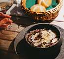 Finely presented risotto in a black bowl, served with bread and a glass of white wine – regional and sustainable dining at Sunstar Hotel.
