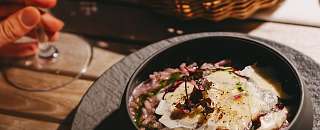 Finely presented risotto in a black bowl, served with bread and a glass of white wine – regional and sustainable dining at Sunstar Hotel.